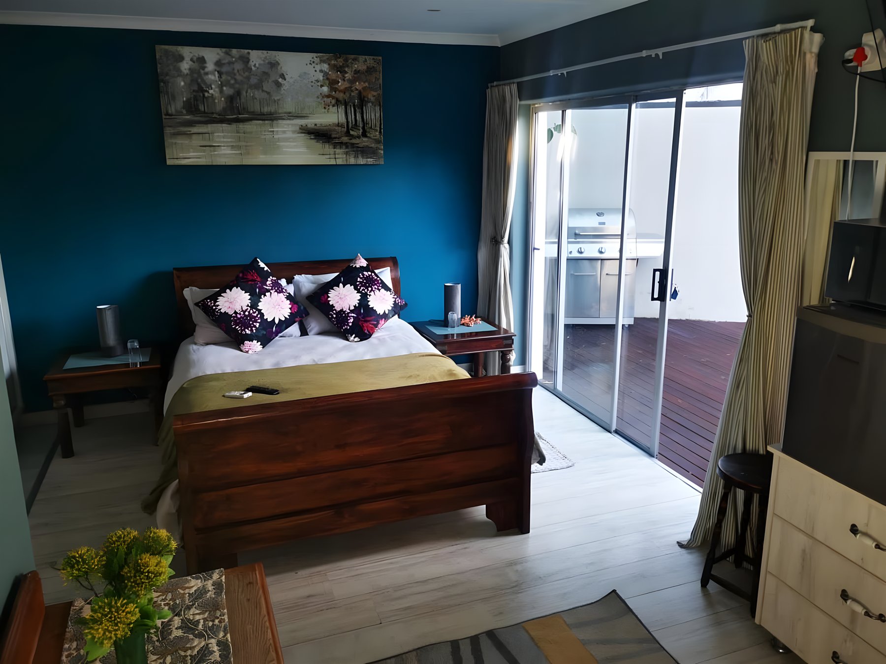 A bedroom with a teal feature wall and wooden bed